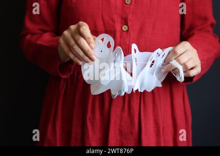 Halloween-Vorbereitungen. Junge Frau mit festlicher Girlande auf schwarzem Hintergrund mit Kopierraum. Halloween-Dekorationen aus nächster Nähe Foto. Stockfoto