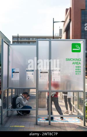 Ausgewiesener Raucherbereich auf der Straße vor dem Bahnhof in Akashi City in Japan. Ein matter Bildschirm, der das Rauchen mit etwas Privatsphäre bietet. Stockfoto