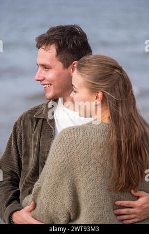 Mit fröhlichen Ausdrücken genießt ein Paar einen verspielten Moment am Meer, ihr Lachen so leicht wie die Meeresbrise, ein Date für zwei verliebte Gäste am Meer Stockfoto