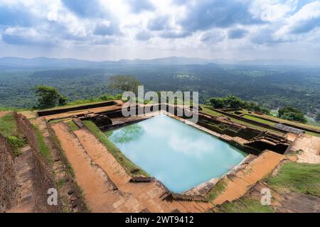 Ein nachmittags Panoramablick vom Gipfel des Sigiriya Rock, mit einer alten Mauerruine, einem riesigen grünen Wald, einem See und weit entfernten Bergketten un Stockfoto