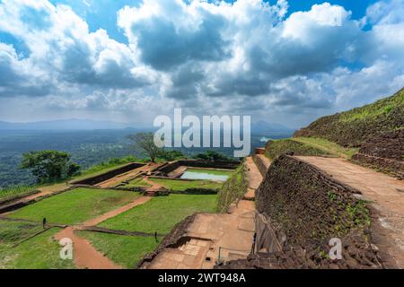 Ein nachmittags Panoramablick vom Gipfel des Sigiriya Rock, mit einer alten Mauerruine, einem riesigen grünen Wald, einem See und weit entfernten Bergketten un Stockfoto