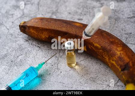 Augsburg, Bayern, Deutschland - 16. März 2024: Spritzen und Medikamente in einer Reifen Banane. Symbolbild der Gentechnik bei Bananen *** Spritzen und Medikamente in einer reifen Banane. Symbolbild Gentechnik Einsatz bei Bananen Stockfoto