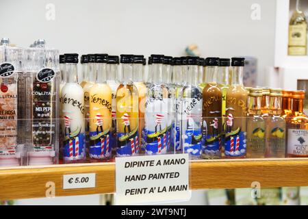 Burano, Italien - 6. Oktober 2019: Kleine Geschenke, handbemalte Flaschen Limoncello und andere traditionelle italienische Liköre im Ladenregal in Venedig. Stockfoto