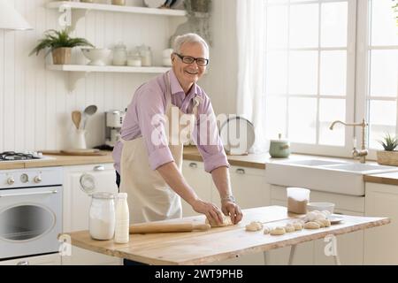 Ein älterer Rentner, der Teig knete, bereitet hausgemachte Backwaren vor Stockfoto