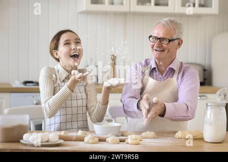 Niedliche Enkelin in Schürze, Spaß mit dem älteren Opa Stockfoto