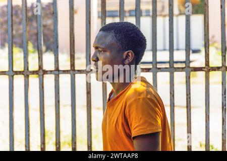 Ein afrikanischer Mann, der vor Einbrecherbars stand, bekam einen mit einem männlichen, rauen Gesicht Stockfoto