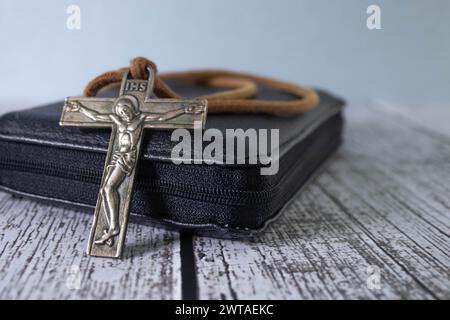 Konzept von Palmensonntag, Karfreitag, Fastenzeit und Karwoche. Bibel, Metallkreuz und grüne Palmenzweige auf hölzernem Hintergrund. Stockfoto