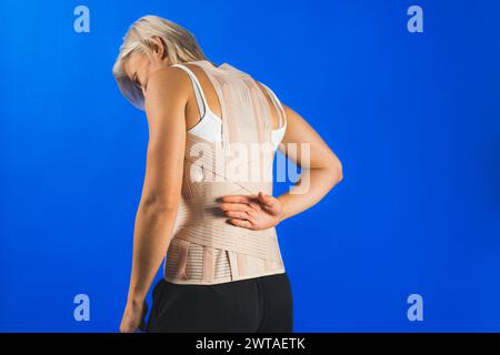 Orthopädisches lumbales Korsett auf dem menschlichen Körper, Rückenschmerzen und Wundversorgung, blauer Hintergrund, Gesundheitswesen. Hochwertige Fotos Stockfoto