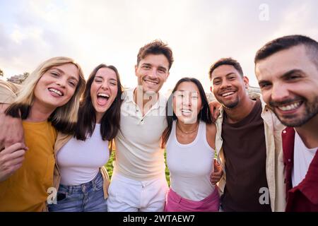 Ein Haufen fröhlicher, multirassischer Freunde, die im Park Spaß haben. Blick auf die Kamera und Lächeln. Stockfoto