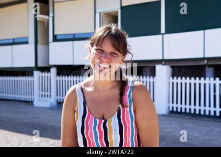 Sommerporträt einer kaukasischen Frau, die am Strand draußen lächelnd in die Kamera schaut. Stockfoto