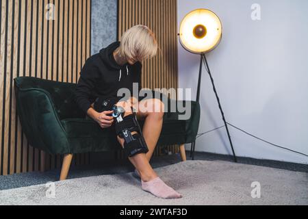 Eine kaukasische Frau, die im Wohnzimmer auf dem Sofa sitzt und eine Kompressionsstütze für die Beine anpasst. Hochwertige Fotos Stockfoto