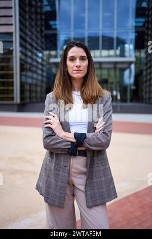 Porträt einer erfolgreichen kaukasischen Frau im Anzug, die selbstbewusst vor der Kamera im Freien posiert. Stockfoto