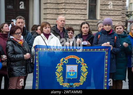 Menschen, die während der Gedenkfeier in der Nähe des Theaters ein Banner hielten. Die Bewohner von Lwiw und die zwangsvertriebenen Bewohner des besetzten Mariupol nehmen an einer Veranstaltung zum Gedenken an die vor 2 Jahren verstorbenen Menschen im Mariupol-Theater in der Nähe des Nationalen Akademischen Operntheaters und Balletts von Solomiya Krushelnytska Teil. Die Bewohner von Mariupol versammelten sich in der Nähe der Theater von Lemberg und vieler Städte der Ukraine und zündeten Gedenklampen an, um an die Toten zu erinnern. Am 16. März 2022 warfen die russischen Besatzungsmitglieder Luftbomben auf die Theater in Mariupol ab, ohne die Inschrift in der Kapitallette zu ignorieren Stockfoto