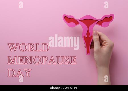 Weltmenopause. Frau, die Papier-Uterus auf rosafarbenem Hintergrund hält, Ansicht von oben Stockfoto