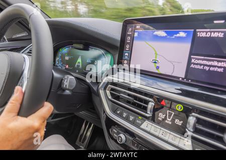 Nahaufnahme der Instrumententafel und des Navigationsbildschirms im Innenraum des BMW iX3 M Elektroautos während der Fahrt auf der Autobahn. Stockfoto