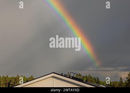 Wunderschöner Blick auf einen Regenbogen über die Dächer der Villa an einem bewölkten Sommertag. Schweden. Stockfoto