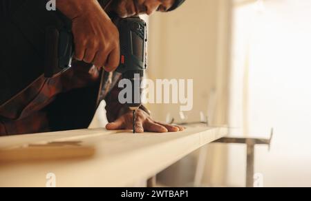 Zimmermann benutzt eine Bohrpistole, um Holzleisten in einer Hausküche zu befestigen. Dieser professionelle Auftragnehmer leitet die Ertüchtigung und Sanierung des Inter Stockfoto