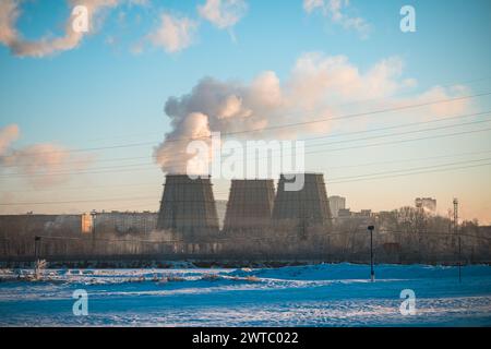 Dampf kommt aus den Rohren eines Kühlturms, einer Fabrik, einer Industriestadt im Winter Stockfoto