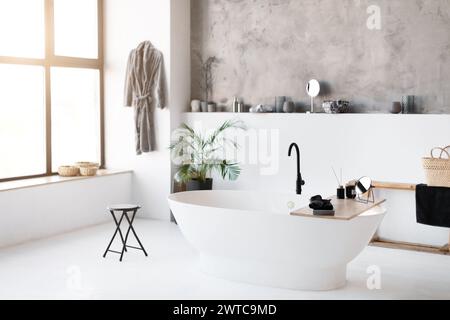 Innenaufnahme des geräumigen, sonnendurchfluteten Badezimmers mit eleganter freistehender Badewanne Stockfoto