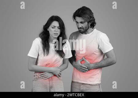 Ein einfarbiges Bild eines Mannes und einer Frau in weißen T-Shirts, beide mit Händen am Bauch Stockfoto