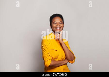 Aufgeregte erfolgreiche Frau lächelt und hat Spaß vor dem Hintergrund des Wandbanners im Studio Stockfoto