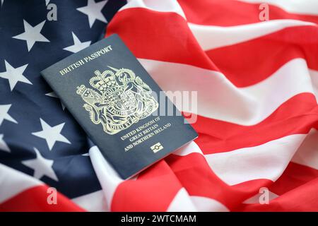 Blauer britischer Pass auf dem Hintergrund der US-Nationalflagge aus nächster Nähe. Tourismus und Diplomatie Stockfoto
