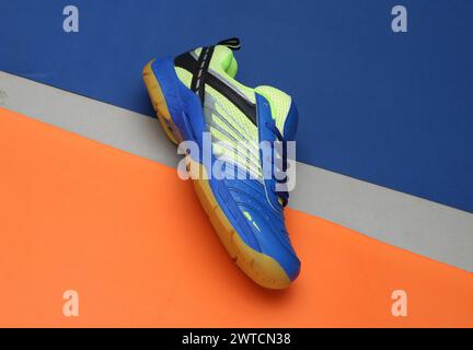 Badmintonschuhe mit kreativem Foto auf orangeblauem Hintergrund Stockfoto