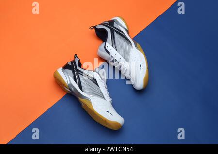 Badmintonschuhe mit kreativem Foto auf orangeblauem Hintergrund Stockfoto