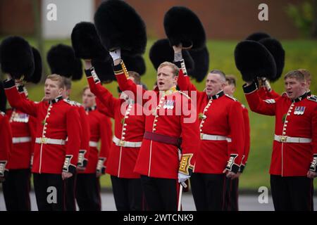 Die irischen Wachmänner heben ihre Kopfbedeckung an, um während einer St. Patrick's Day-Parade auf dem Parade Square in den Mons Barracks in Aldershot zu jubeln. Bilddatum: Sonntag, 17. März 2024. Stockfoto