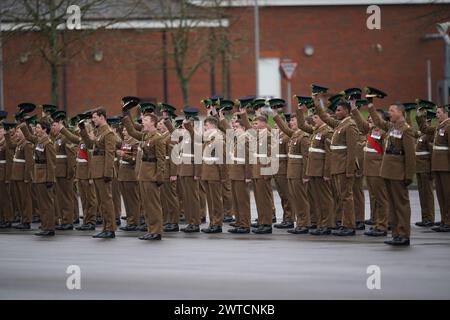 Die irischen Wachmänner heben ihre Kopfbedeckung an, um während einer St. Patrick's Day-Parade auf dem Parade Square in den Mons Barracks in Aldershot zu jubeln. Bilddatum: Sonntag, 17. März 2024. Stockfoto