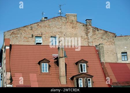 Gebäudewand in schlechtem Zustand über dem roten Metalldach in der Altstadt von Riga, Vorderansicht Stockfoto