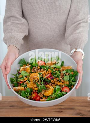 Frau mit bunten grünen Blättern Erdbeeren Mandarine Walnüsse Salatschüssel Stockfoto