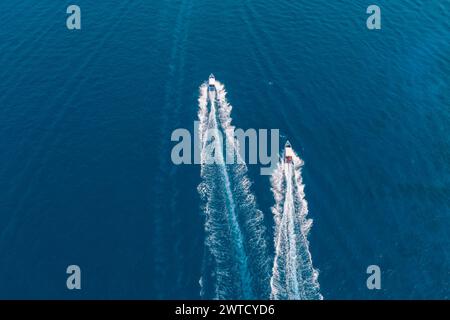 Blick von oben auf ein Paar mit zwei Booten, das zum blauen Meer segelt. Drohnenblick auf Segelwettbewerbe, Rennen. Motorbootfahrt auf See. Stockfoto