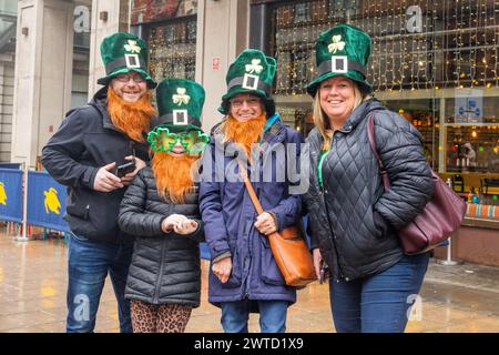 Leeds, Großbritannien. MÄRZ 2023. Zuschauer, die guiness-Hüte und lange Fake-Bärte tragen, lächeln und feiern, wenn der St. Patricks Day march 2024 vorbeizieht. Credit Milo Chandler/Alamy Live News Stockfoto