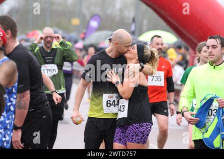 Colchester, Großbritannien. März 2024. Der Colchester Half Marathon fand heute statt, um den Robin Cancer Trust zu unterstützen. Trotz des starken Regens starteten rund 2.500 Läufer das Rennen im Jwatch Community Stadium, dem Heimstadion des Colchester United FC. Ein Paar feiert, dass das Rennen beendet ist. Credit:Eastern Views/Alamy Live News Stockfoto