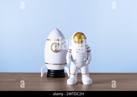 Spielzeugrakete und Astronautenfigur. Raumfahrer und Shuttle auf Holztisch über blauem Hintergrund mit Kopierraum. Kinder träumen von der Zukunft des Weltraums Stockfoto