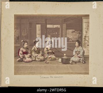 Japanische Teezeremonien. Zugeschrieben von Adolfo Farsari, Fotograf (Amerikaner, 1841–1898) etwa 1875–1890er Jahre, sitzen vier Frauen um eine eiserne Brazier herum, die normalerweise bei einer japanischen Teezeremonie verwendet wird. Eine der Frauen schaut hinunter auf einen 'Chawan' oder eine Teeschale, die sie in den Händen hält. Die gemalte Kulisse zeigt ein „Tokonoma“ oder eine Nische mit einer hängenden Rolle und anderen Objekten. (Recto, Mount) untere Mitte, in schwarzer Tinte: "Japanische Teezeremonien"; Stockfoto