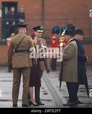 Mons Barracks, Aldershot, Hampshire, Großbritannien. März 2024. Das Regiment der Irish Guards versammelt sich in einer speziellen St. Patrick's Day Parade und Feier in Aldershot. Die Parade ist ein Höhepunkt des Jahres für dieses Zweirollen-Regiment. Lady Ghika, Ehefrau des Regimentsleutnant Colonel, Major General Sir Christopher Ghika, überreicht Shamrock an Offiziere, Seamus und Haftbefehler, die es wiederum entlang der Reihen ausstellen. Die Parade endet mit einem vormarsch, bei dem der Oberstleutnant des Regiments, Generalmajor Sir Christopher Ghika, den Gruß abnimmt. Kredit: Malcolm Park/Alamy Stockfoto