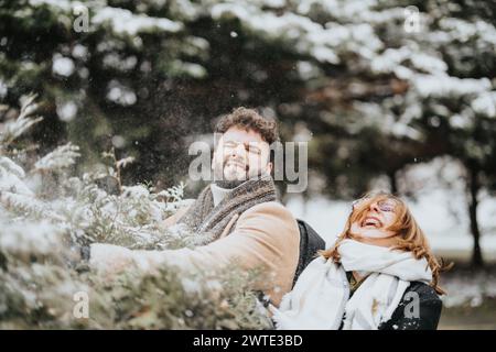 Zwei junge Menschen teilen einen Moment der Freude und Spontaneität. Sie lachen, während sie einen verschneiten Tag genießen, was eine Mischung aus Arbeit und Vergnügen zeigt. Stockfoto