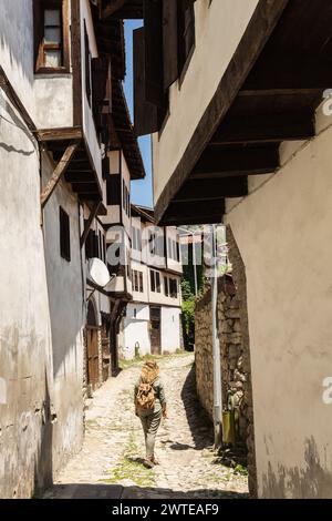 Junge Frau, die auf der Kopfsteinpflasterstraße von Safranbolu in der türkischen Provinz Karabuk läuft Stockfoto