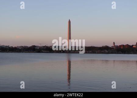 Kirschblüten bei Sonnenuntergang neben dem Tidal Basin und dem Washington Monument, einschließlich einer Reflexion des Monuments Stockfoto