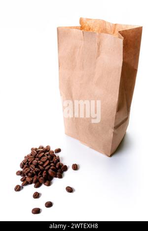 Geröstete Kaffeebohnen verschüttet vor einer braunen Einwegverpackung aus Bastelpapier auf weißem Hintergrund. Recycelbares und nachhaltiges Modell Stockfoto