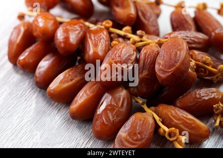 Süße getrocknete Datteln auf einem Zweig auf einem Küchenbrett. Orientalische Leckereien. Gesunder nahrhafter Snack. Stockfoto