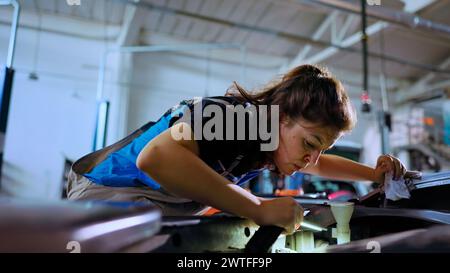 POV-Aufnahme eines akribischen Ingenieurs, der die Motorhaube in der Werkstatt öffnet und bei der routinemäßigen Wartung mithilfe des Arbeitsscheinwerfers auf Schäden überprüft. Werkstattarbeiter mit professionellem Werkzeug, um in das Auto zu schauen Stockfoto