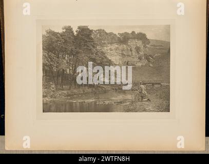 Wolfscote Bridge und Franklyn Rock, Beresford Dale. Captain George Bankart, Fotograf (Britisch, 1829–1916) 1888 Blick auf den Fluss Taube, der durch den Beresford Dale führt und Franklin Rock in der Ferne sichtbar ist. Ein Mann, der eine Angelrute hält, kniet am Ufer nieder, mit einem Korbkorb, der auf dem Rücken geschnallt ist, und einem langen Netz, das neben ihm auf dem Boden liegt. Eine Holz- und Steinbrücke überquert den Fluss im Hintergrund. Die Initialen des Fotografen, „GB“, wurden in die untere linke Ecke des Bildes eingekratzt. (Recto, angrenzendes Interleaving) Mitte, gedruckt in schwarzer Tinte: 'PLATE LIV. WOLFSCO Stockfoto