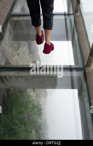 Touristen spazieren entlang des Cliff Hanging Walkway, der sich an den Kanten der senkrechten Klippe der Gipfel des Tianmen Berges anschmiegt. Stockfoto