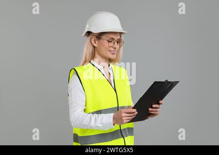 Ingenieur im Schutzhelm mit Klemmbrett auf grauem Hintergrund Stockfoto