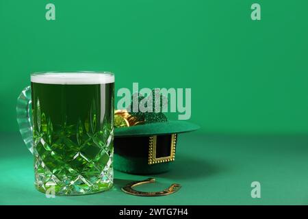 St. Patrick's Day Party. Grünes Bier, Leprechaun Hut mit Gold, Hufeisen und dekorativem Kleeblatt auf grünem Hintergrund Stockfoto