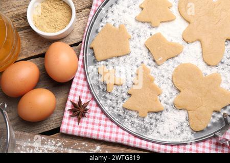Zutaten und rohe Weihnachtsplätzchen in verschiedenen Formen auf Holztisch, flach gelegt Stockfoto