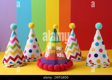 Verschiedene helle Partyhüte mit Pompons auf farbigem Hintergrund Stockfoto